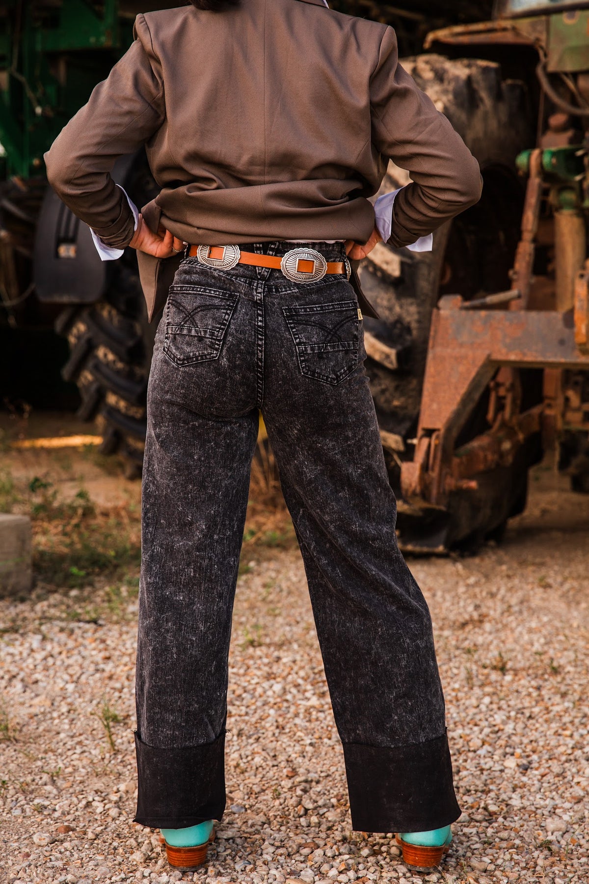 Rear fit of Honey Black Stone jeans with wide legs and decorative back-pocket stitching, paired with a concho belt and boots.