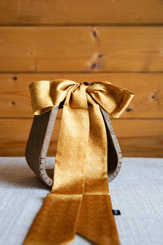 Gold Fly Hound Twilly by 2 Fly Co tied in a bow, showing its tonal houndstooth pattern and long, pointed scarf ends.