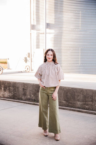 Model facing forward in the Autumn Ridge Plaid Blouse, olive wide-leg jeans and neutral boots, with one hand in a pocket.