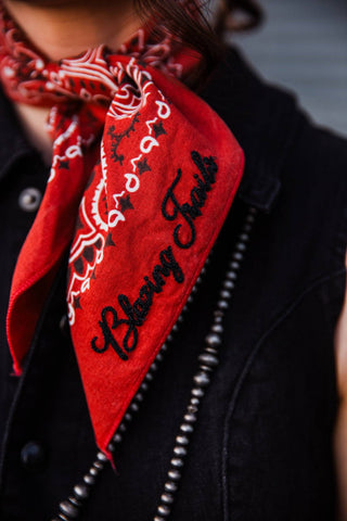 Black Blazing Trails chainstitch lettering on a red patterned bandana, knotted over a black collared dress.