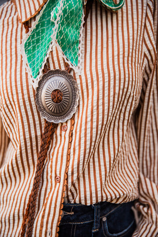 Close-up of the Buck Scallop Top showing brown-and-cream stripes, brown buttons and scalloped trim along the front placket.