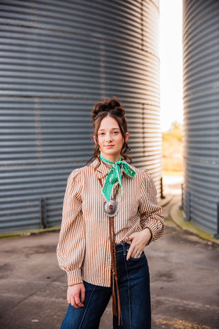 Sadie wearing the brown-and-cream striped Buck Scallop Top with gathered long sleeves, styled with a green scarf and dark jeans.