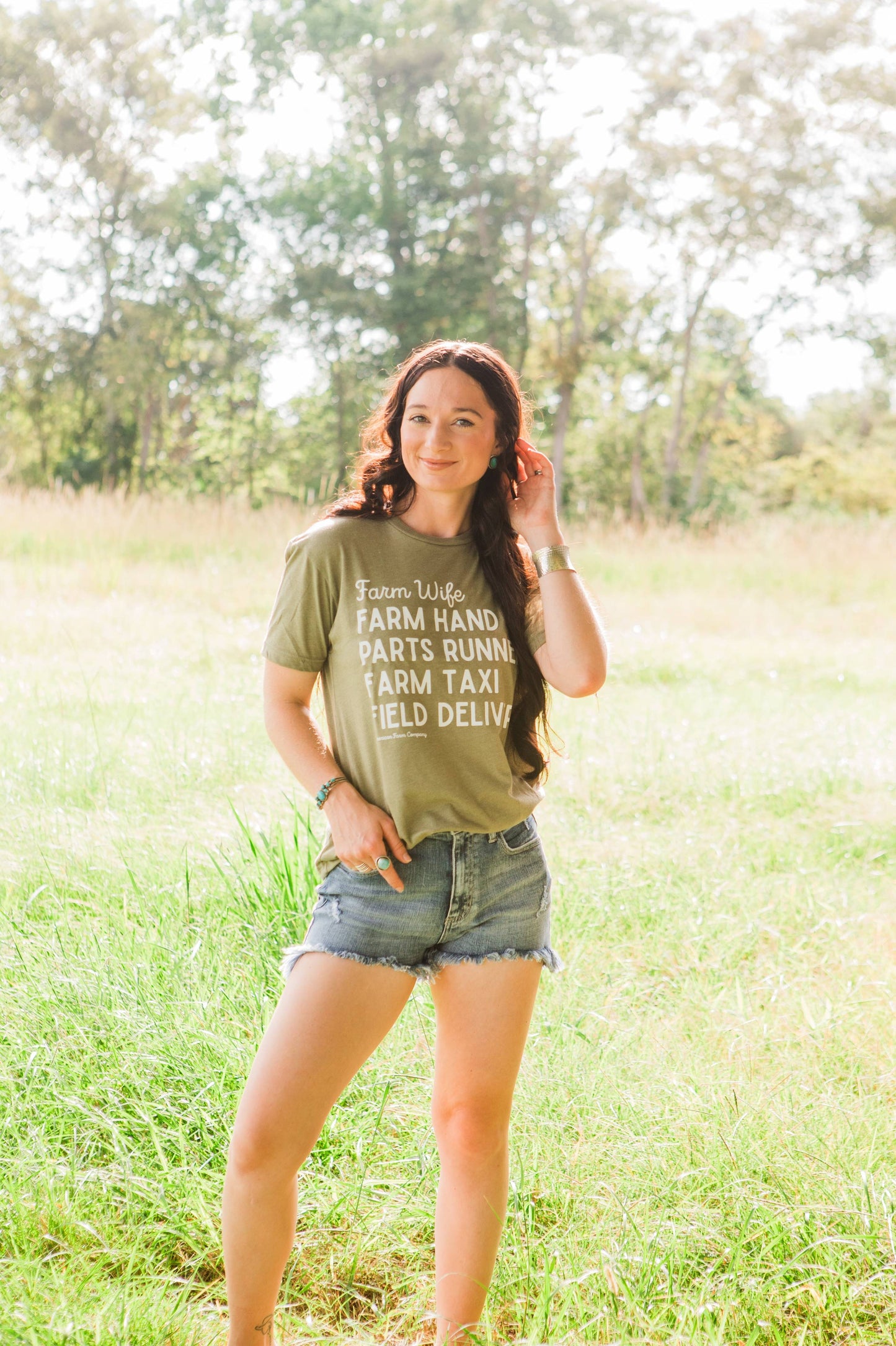 Woman wearing a green t-shirt with text in a grassy field
