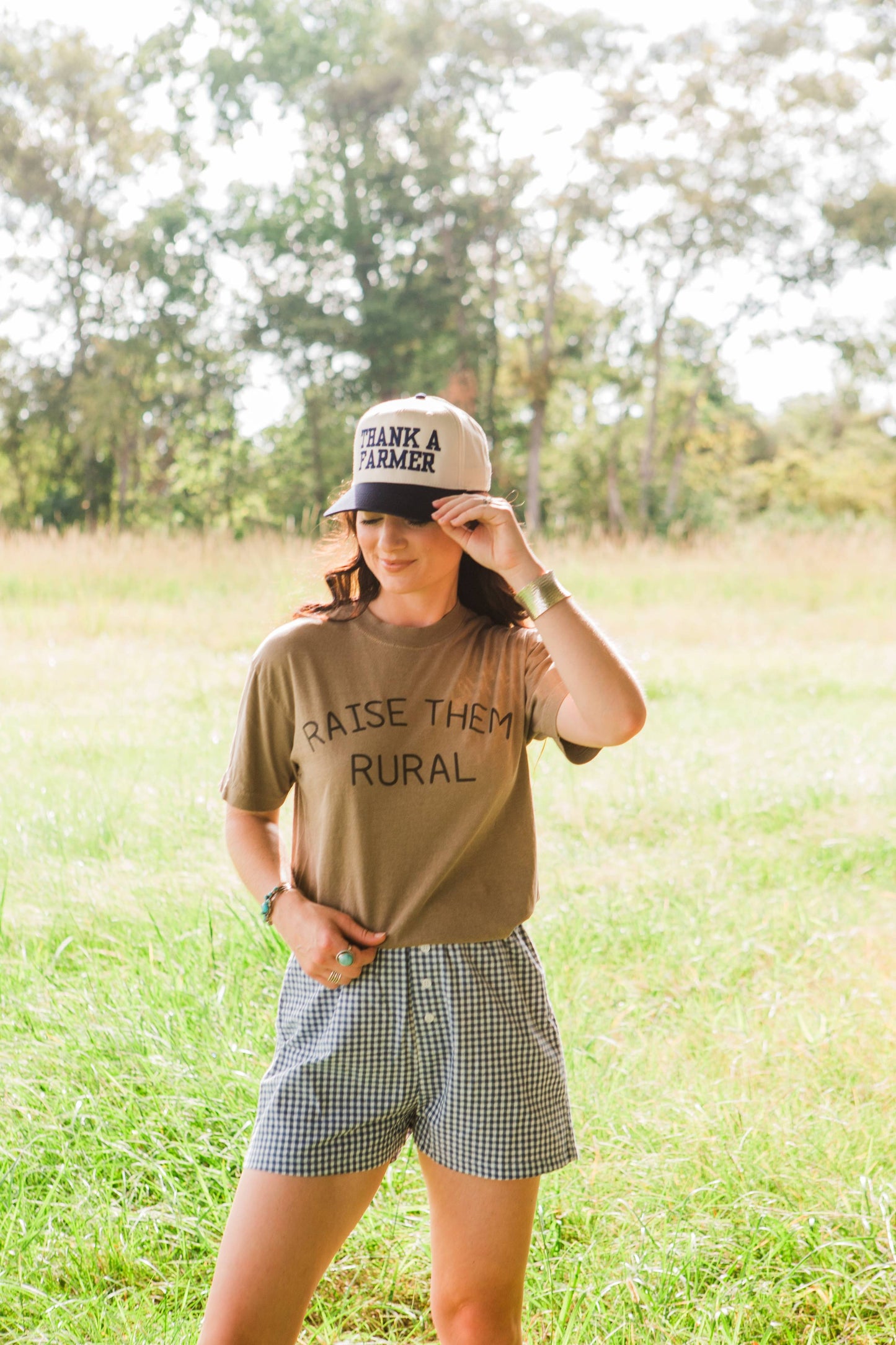 Person wearing a t-shirt with text and a cap in a grassy field