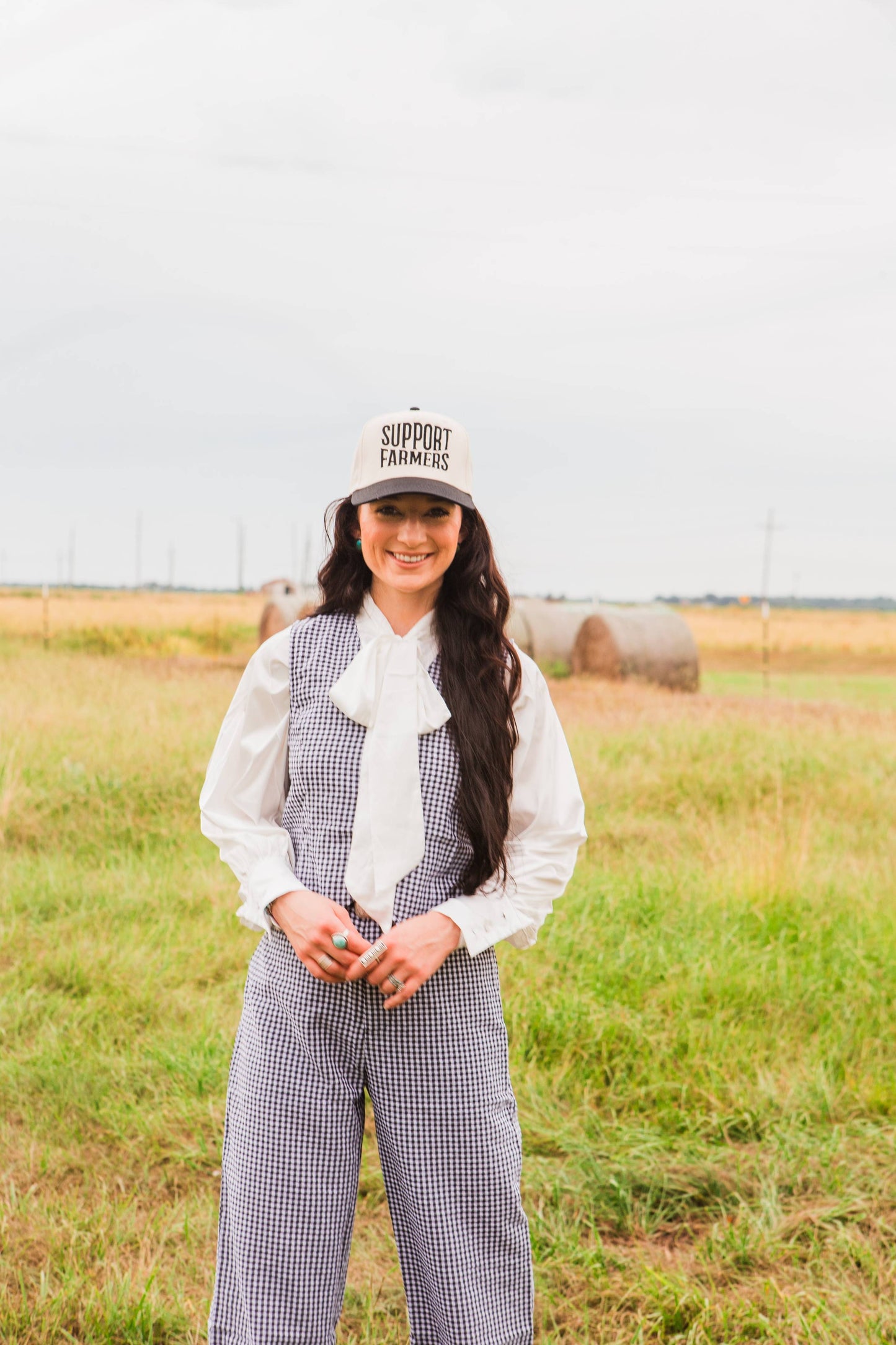 Woman wearing a cap with 'Support Local Farmers' text in a field