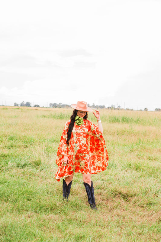 Person wearing a colorful dress and black boots standing in a field