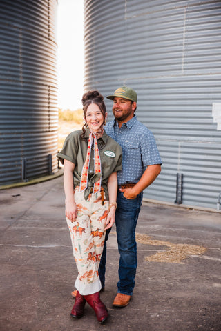 Trevor in the blue patterned Emerson pearl snap, laughing beside Sadie between metal grain bins.