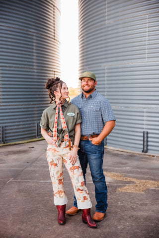 Trevor wearing the blue patterned Emerson short-sleeve pearl snap with jeans and brown boots, standing beside Sadie.