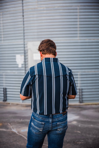 Back view of the navy Hatfield in Blue pearl snap showing white vertical stripes, short sleeves and a Western back yoke.