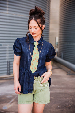 Angled view of the High Roller denim top showing puff sleeves, curved Western stitching and a gathered waist.
