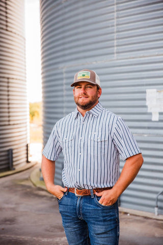 Front view of Trevor in the striped Jack in Black short-sleeve pearl snap, tucked into jeans with a tooled leather belt.