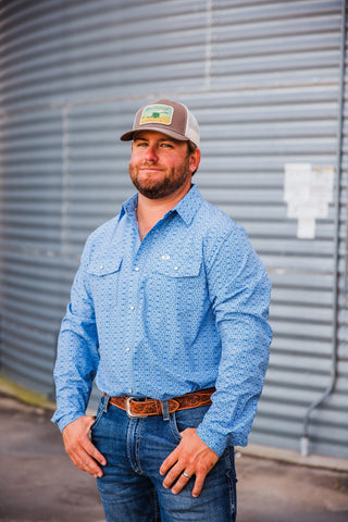 Trevor wearing the blue patterned Jesse pearl snap with two flap chest pockets, styled with jeans and a tooled leather belt.