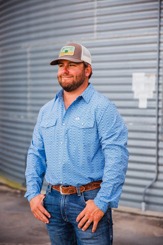 Trevor styling the blue patterned Jesse pearl snap with blue jeans, a brown tooled leather belt and a trucker cap.