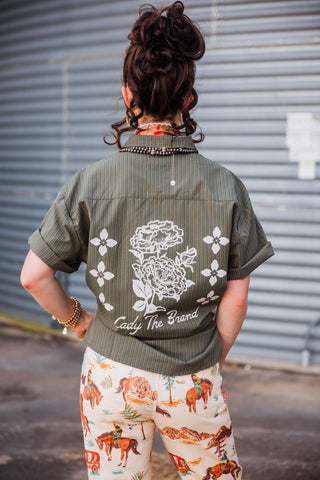 Lady Mechanic shirt back showing a large white floral design, Lady The Brand lettering and turned-up short sleeves.