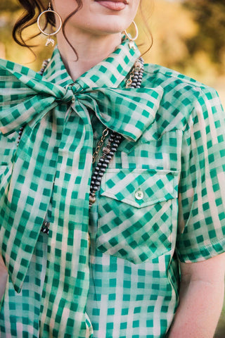 Detail of the Laurel Gingham Sheer Top showing a buttoned flap chest pocket, sheer green checks and neckline bow. lady the brand