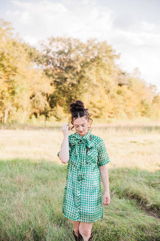 Sadie wearing the green Laurel Gingham Sheer Top styled as a dress with a bow neckline and Western boots.