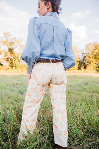 Back view of cream Paisley Horse Pants showing horse and horseshoe print, belt loops and straight legs.