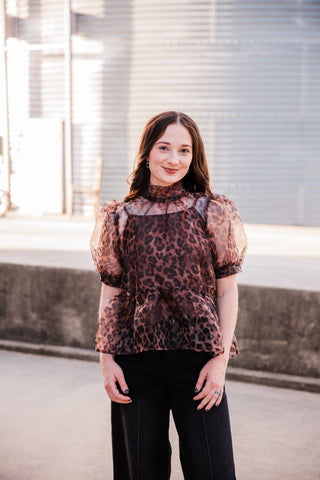 Front view of the Sable Leopard Blouse showing sheer short puff sleeves, a high neckline and a peplum hem.