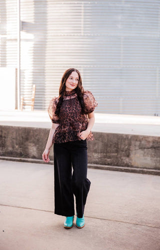 Model wearing the Sable Leopard Blouse with black wide-leg pants and turquoise Western boots.