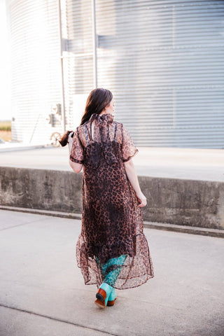 Back view of the Sable Leopard Maxi Dress showing the neck bow, upper-back opening and sheer leopard-print overlay.
