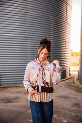 Front view of the Sunset Cowboy Cardigan showing pink buttons, horse and cactus motifs, and turned-back knit cuffs.