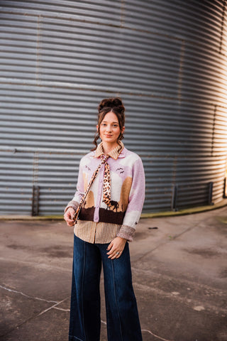 Sadie styling the Sunset Cowboy Cardigan over a striped blouse with a leopard-print neck scarf and dark wide-leg jeans.