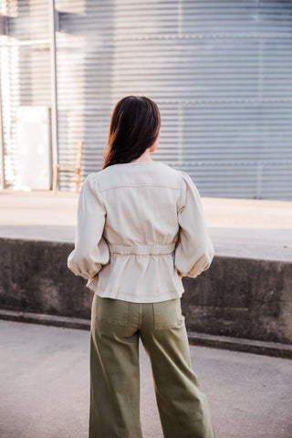 Back view of the cream Sutton Top showing its gathered waist, three-quarter puff sleeves and flared hem.