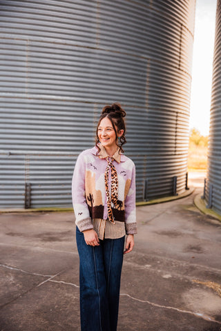 Sadie wearing the leopard-print Meowdy twilly tied at her collar, with long ends layered over a pastel Western cardigan.