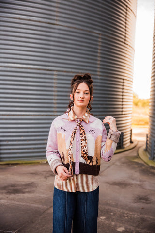 Front view of the leopard-print Meowdy twilly knotted beneath a striped collar, its narrow ends draped over a pink cardigan.