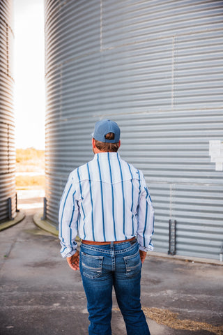 Back view of the blue-striped Tristan pearl snap showing the back yoke and long sleeves, tucked into blue jeans.