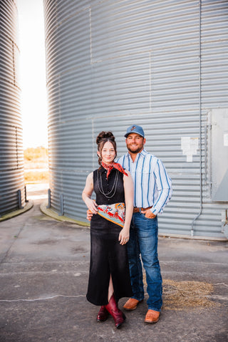 Trevor in the blue-striped Tristan long-sleeve pearl snap and jeans, posing with Sadie beside a metal grain bin.