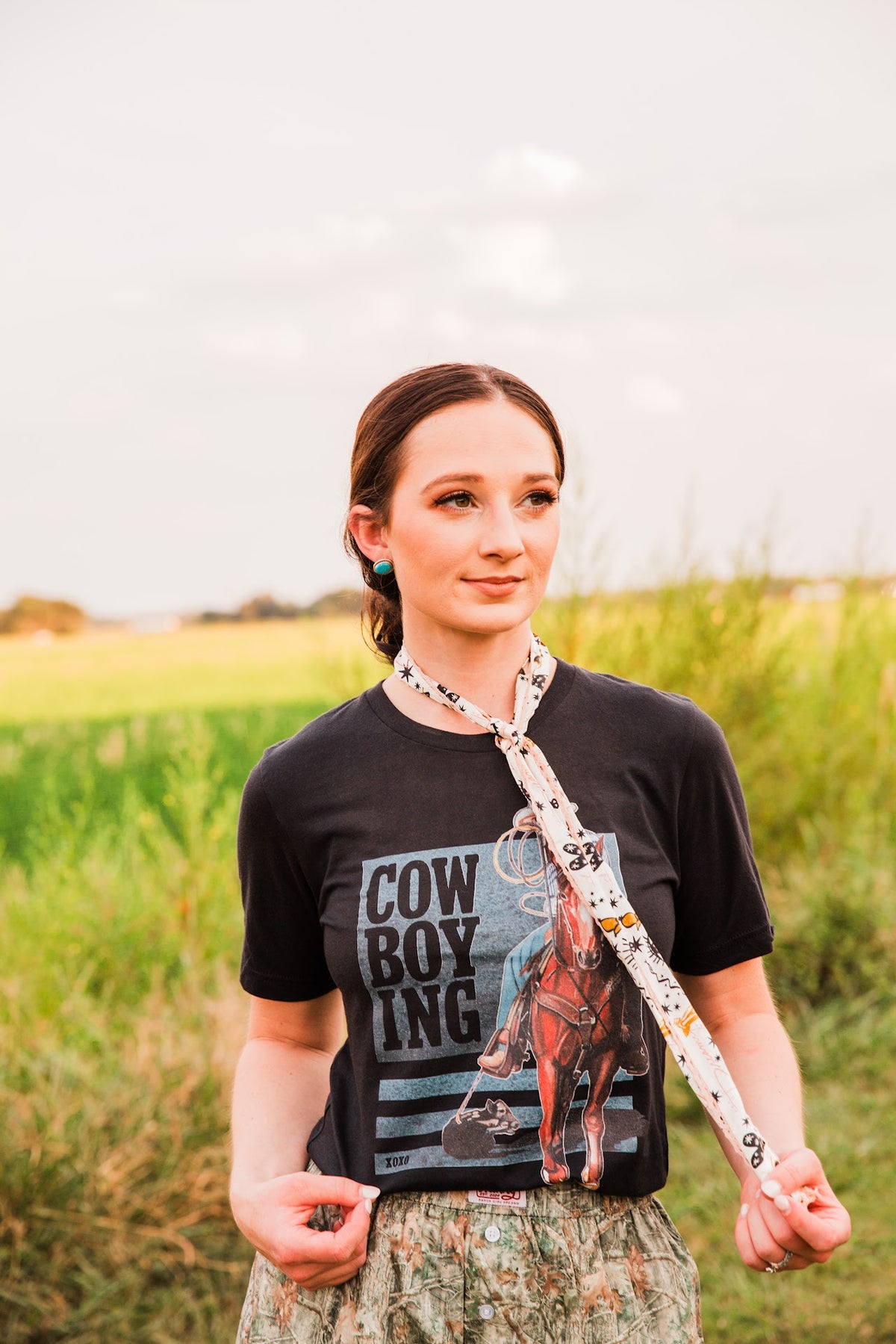Dreamy Sketches Twilly worn as a long neck tie with a black cowboy graphic tee and camo shorts, with one end held out.