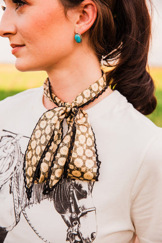 Josephine Twilly by Allie Falcon tied in a neck bow, showing cream doily motifs on a dark background with black crochet trim.