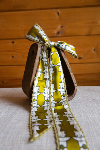 Allie Falcon Mod Maud silk twilly with long pointed tails, yellow and white western profile artwork and olive crochet edges.