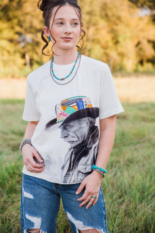 Allie Falcon Reverie Tee close-up showing the cowboy portrait, colorful patterned hat, crew neckline and short sleeves.