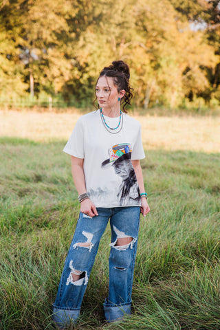 White Reverie Tee by Allie Falcon with a colorful cowboy graphic, worn with distressed wide-leg jeans in a full outfit view.