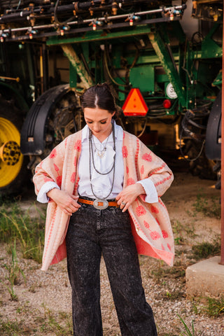 Allie Falcon Winnie Boyfriend Cardigan worn open, revealing its pink interior above washed black jeans and a Western belt.