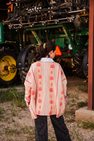 Rear view of the Winnie Boyfriend Cardigan by Allie Falcon, showing its long relaxed drape and pink floral print over black jeans.
