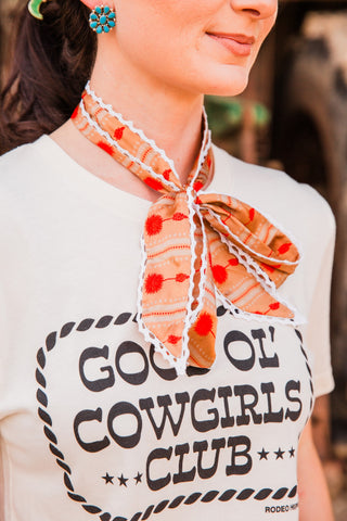 Winnie Twilly by Allie Falcon tied in a neck bow, showing a peach floral print, orange-red motifs and white scalloped trim.