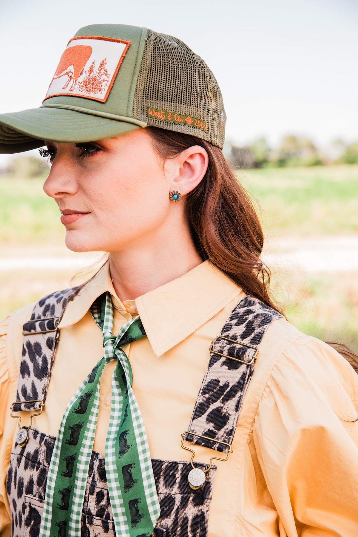 Profile view of a model wearing a sterling silver concho stud earring, showing its turquoise center and small size on the ear.