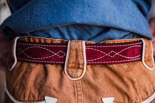 Close-up of premium burgundy suede belt with white contrast stitching and silver buckle