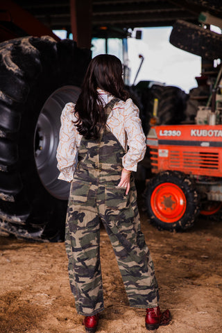 Back view of women’s camo barrel overalls with adjustable straps, back pockets and relaxed fit