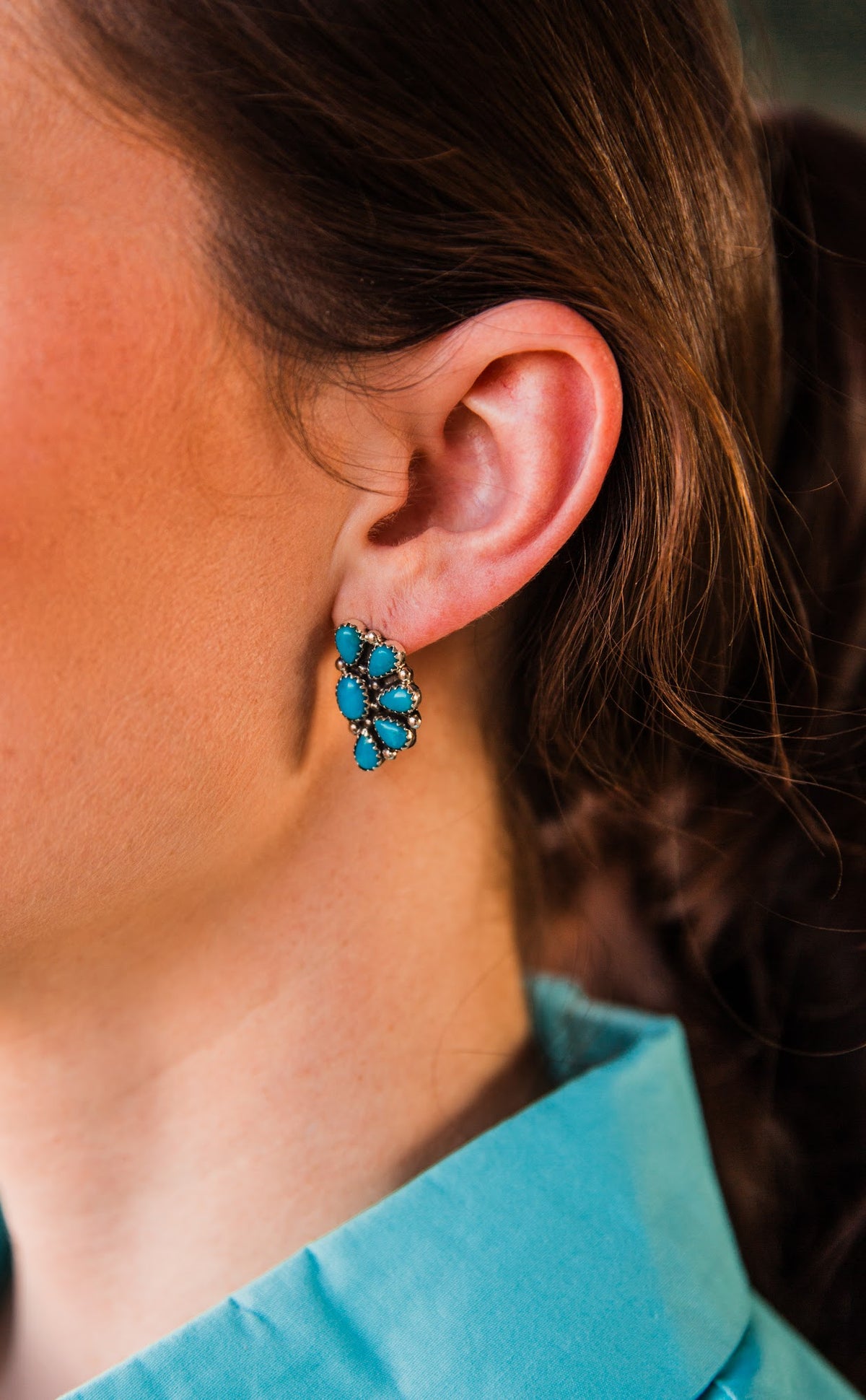 Close-up of a Blue Ridge Half Cluster Earring with genuine turquoise stones in sterling silver, shown on the ear.