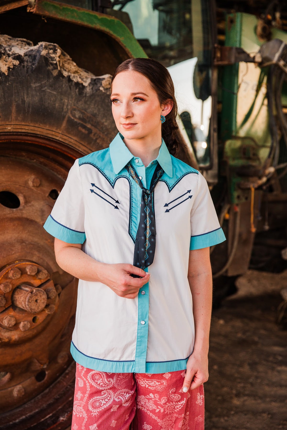 Model wearing Blue Ridge Half Cluster turquoise earrings with her hair pulled back, holding a navy scarf over a Western shirt.
