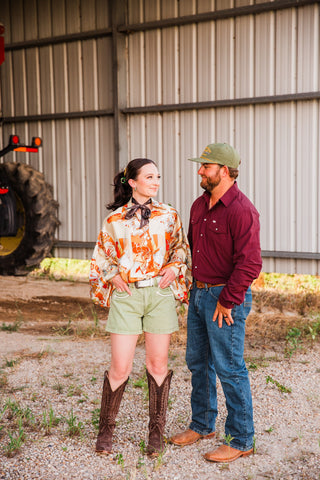 Bronco Boot Top styled with a dark neck scarf, green shorts and tall brown cowboy boots in a full-length couples photo.
