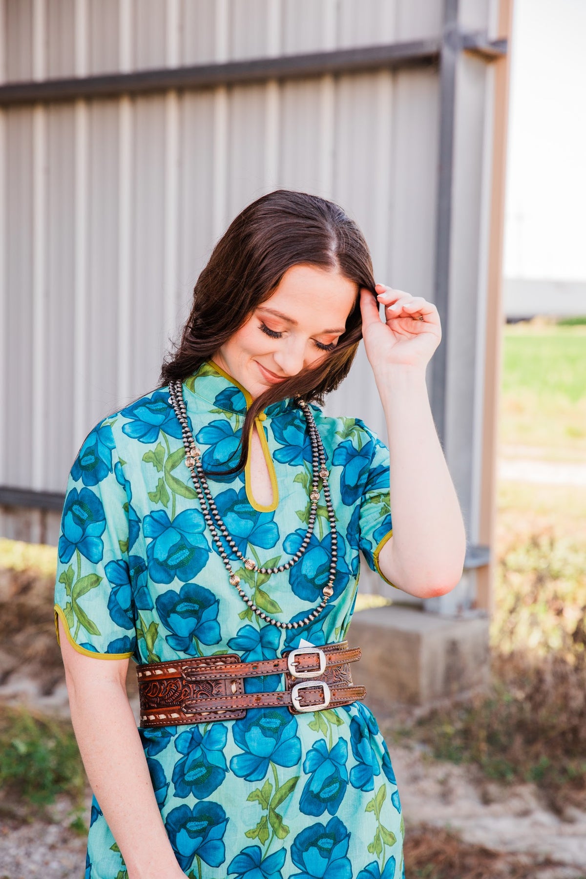 Angled view of the Brown Vintage Buck Stitched Belt, showing double leather straps and silver-tone buckles over a floral dress.