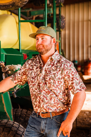 Angled view of a model wearing the Camo Lite short sleeve pearl snap shirt, showing its camo print and chest pockets.