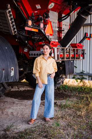 butter yellow women’s button down top styled with light wash wide leg jeans and Western belt