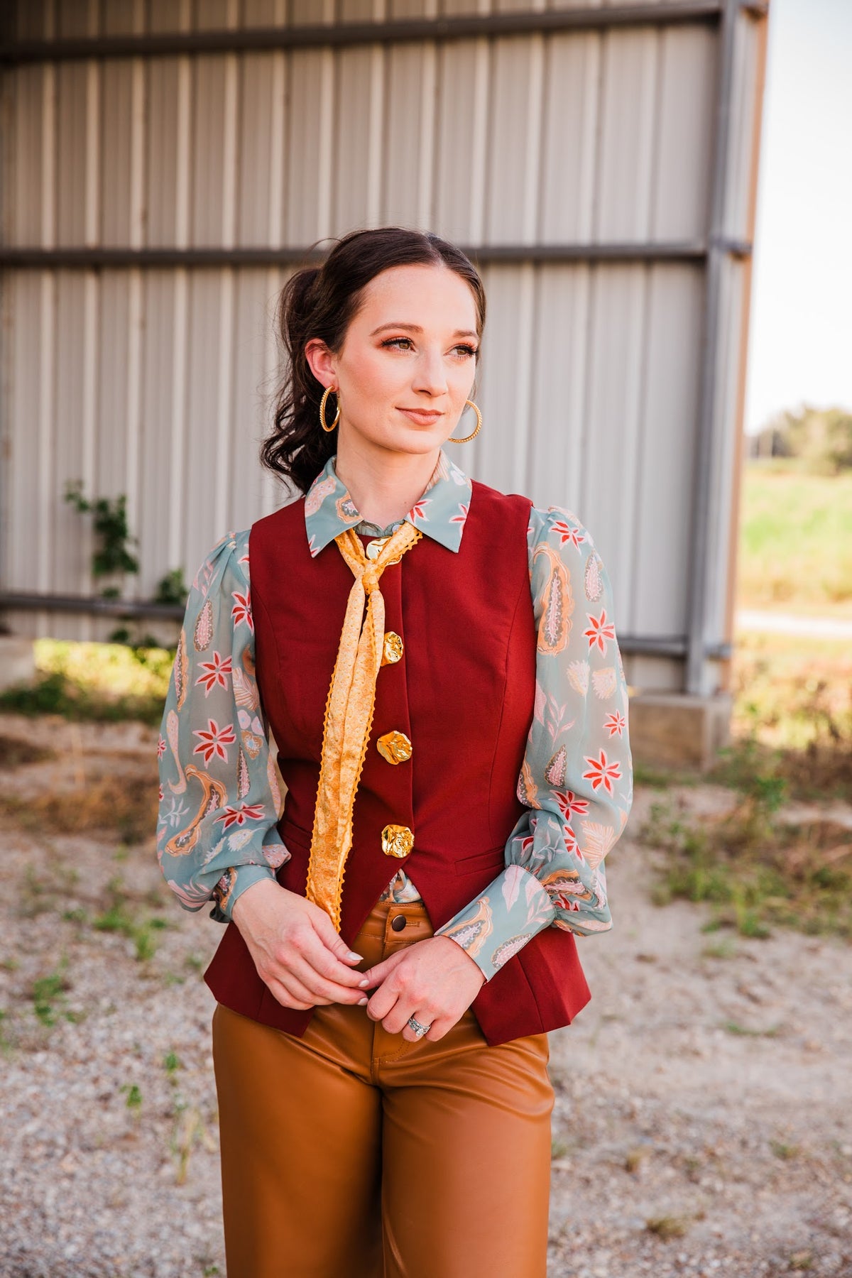 Carmen Vest in burgundy with a tailored waist and gold-tone buttons, layered over a sage paisley blouse with a yellow scarf.