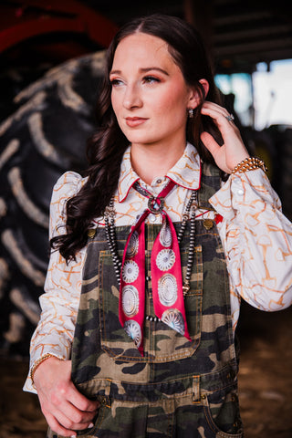 Close-up of Shawnee camouflage bib overalls styled with Western pearl snap shirt and cowgirl accessories